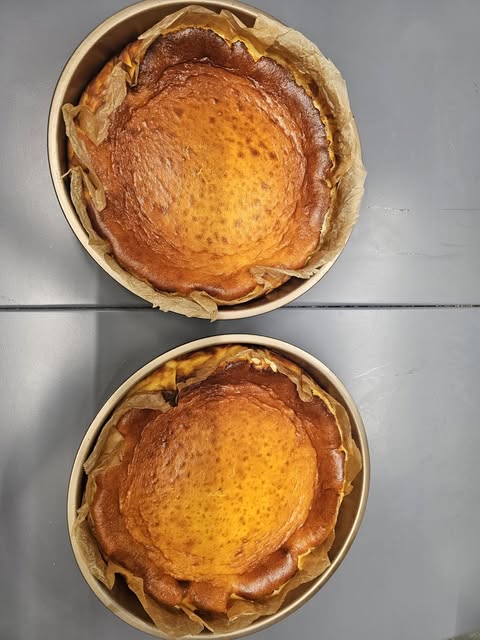 Zwei Burned Basque Cheesecakes von oben, frisch aus dem Ofen in ihren Formen