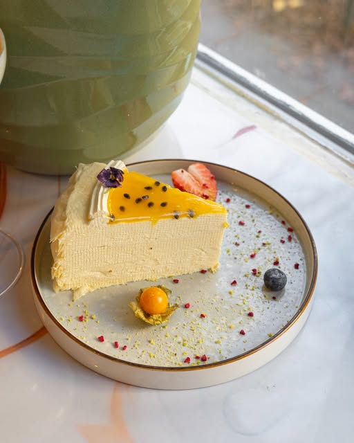 Stück Käsekuchen mit Mango und Physalis auf hellem Teller